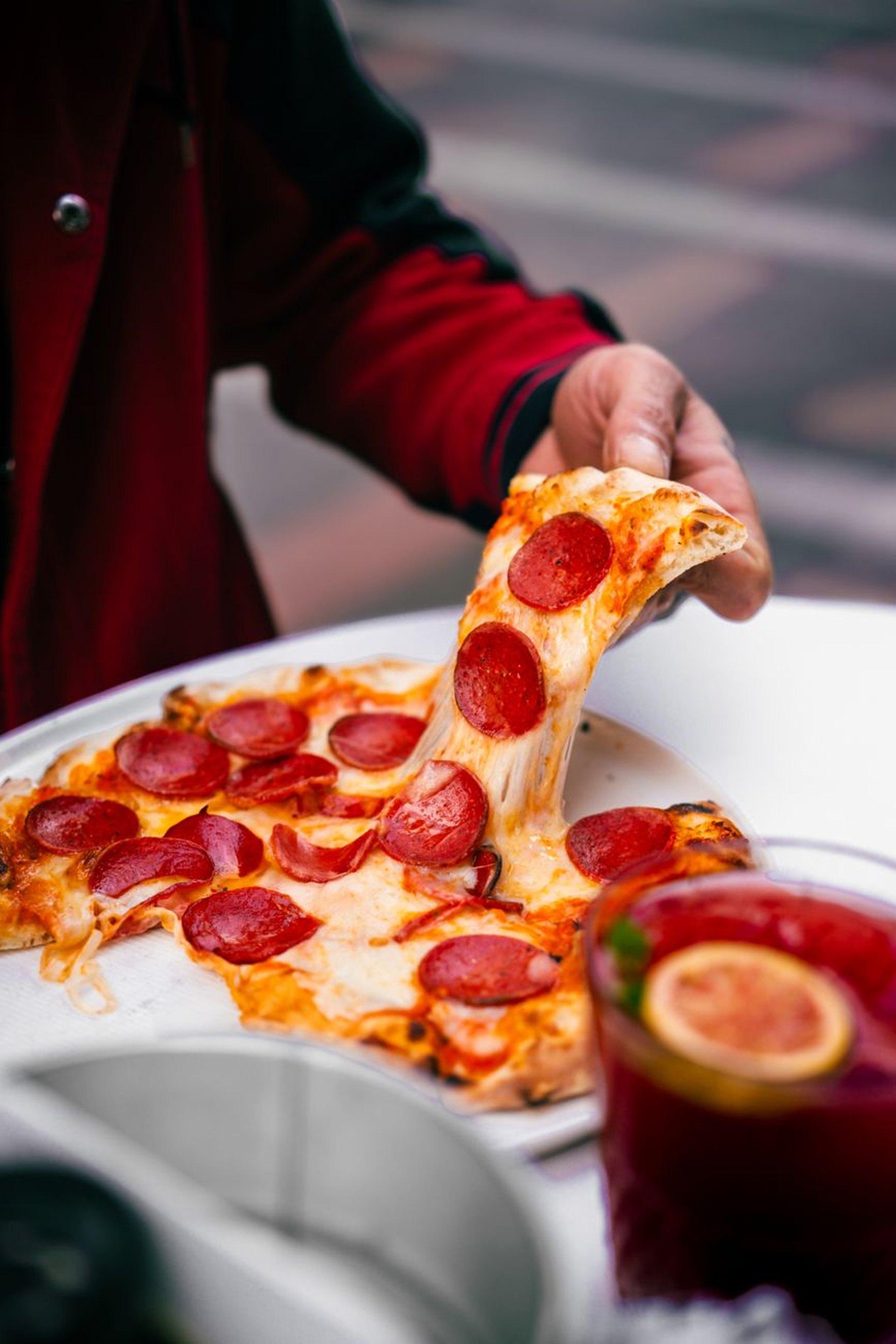 Valaki egy elviteles dobozból eszik, körülötte gyros, pizza és köretek.