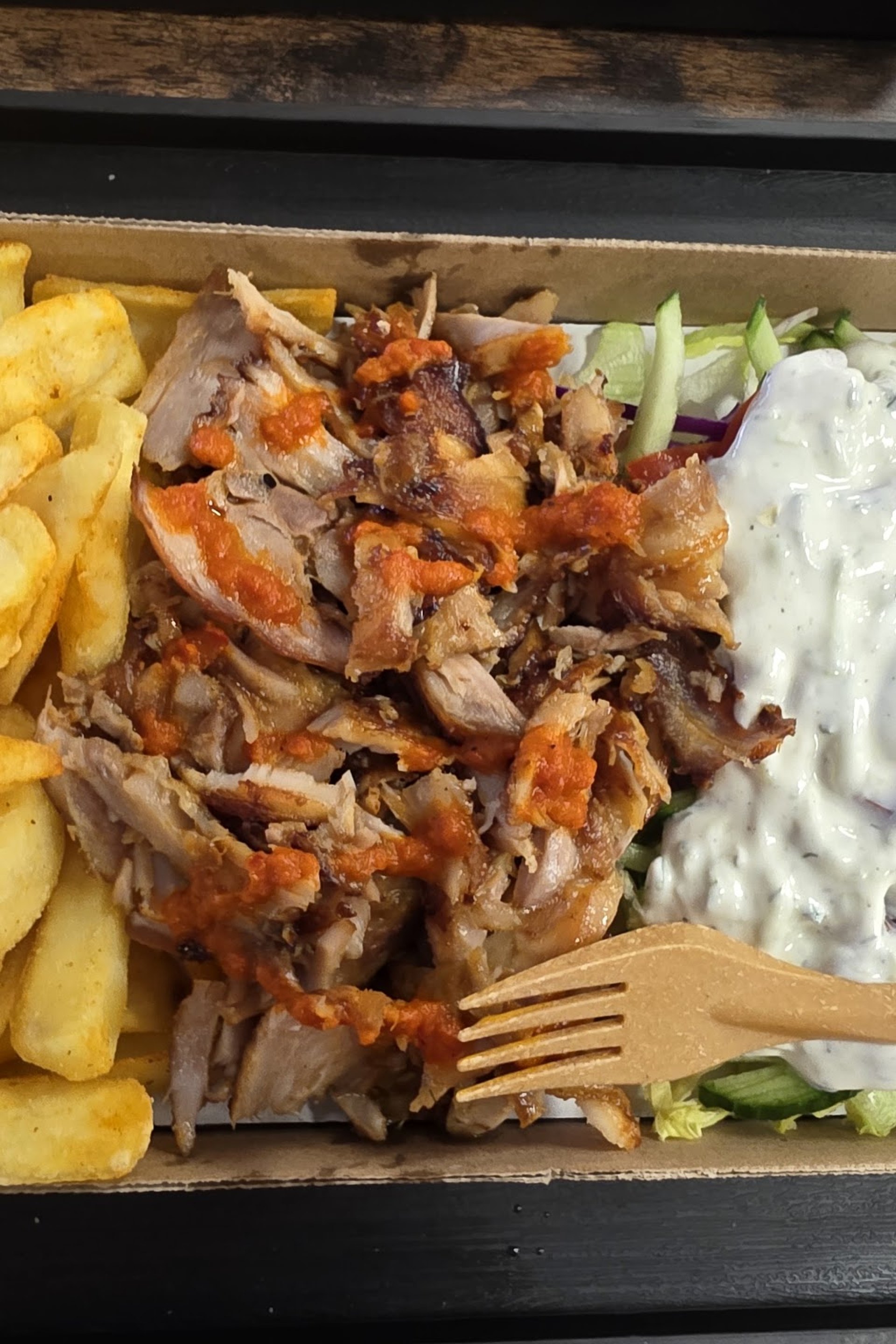 Felülnézet: kezek pizzaszeleteket és ropogós csirkét vesznek el az asztalról, üdítőkkel.