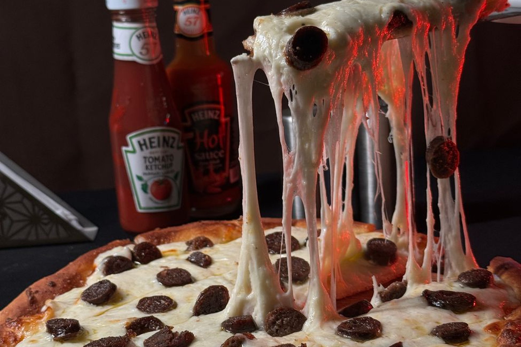 Három mosolygó barát nevetve eszik együtt pizzaszeleteket.